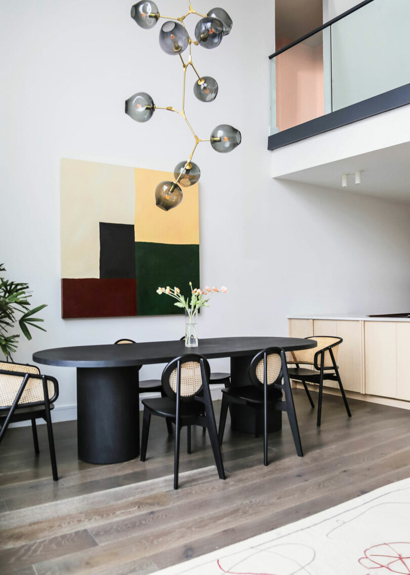 Double height dining room space with a chandelier and dining set.