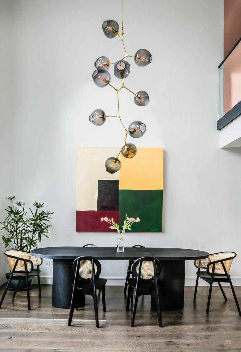 Double height dining room space with a chandelier and dining set.
