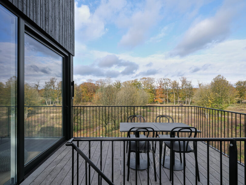 A table and chairs on a deck of an elevated house.