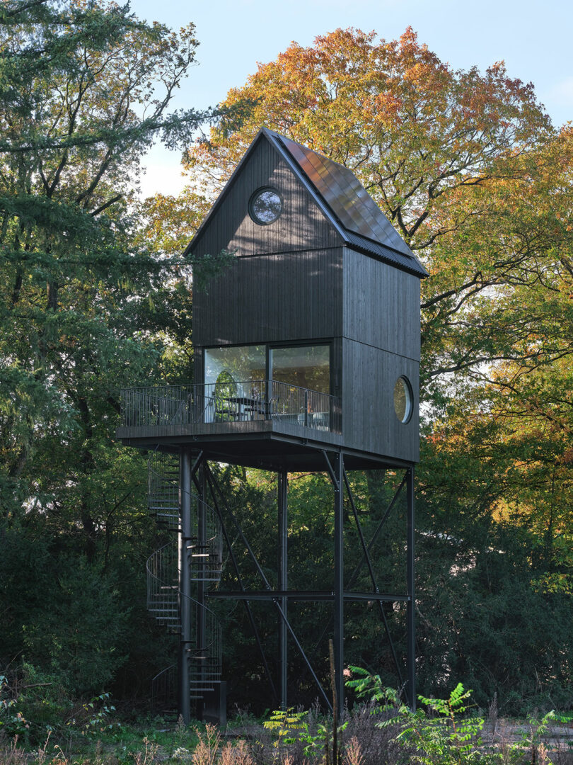 A tall wooden cabin with a balcony and stairs.
