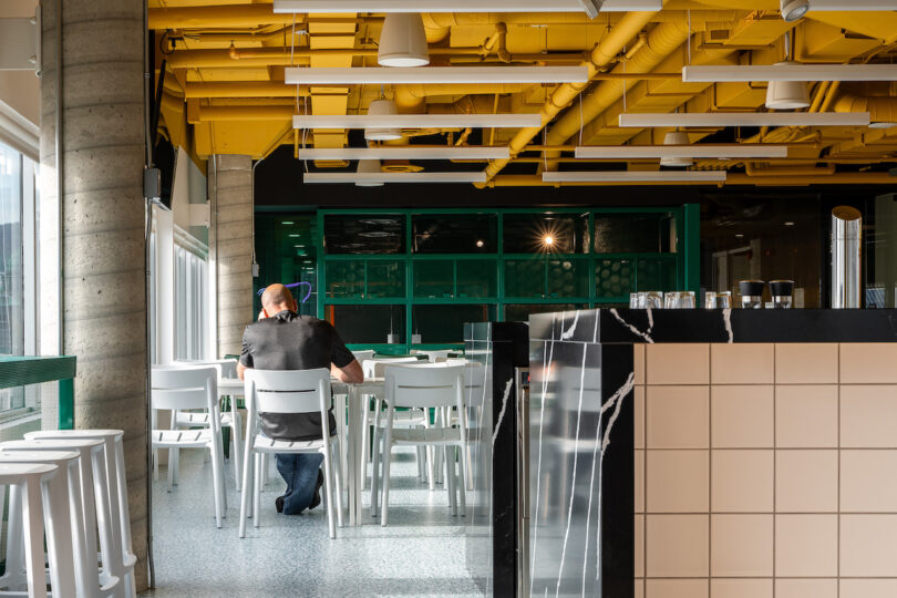 A man is sitting at a table in a eating area of an office.