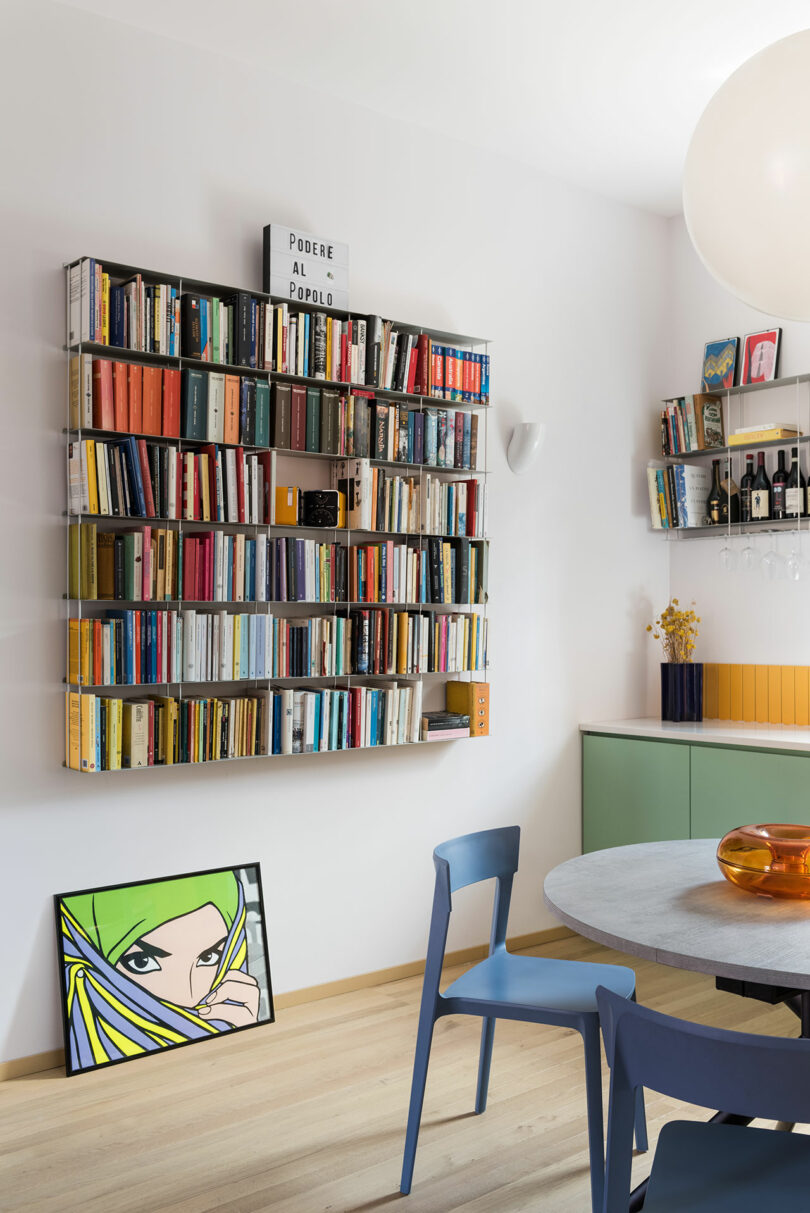A kitchen with a table and chairs and a book shelf.