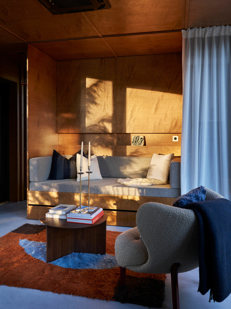 Cozy modern living room bathed in warm sunlight with stylish furnishings and colorful accents.