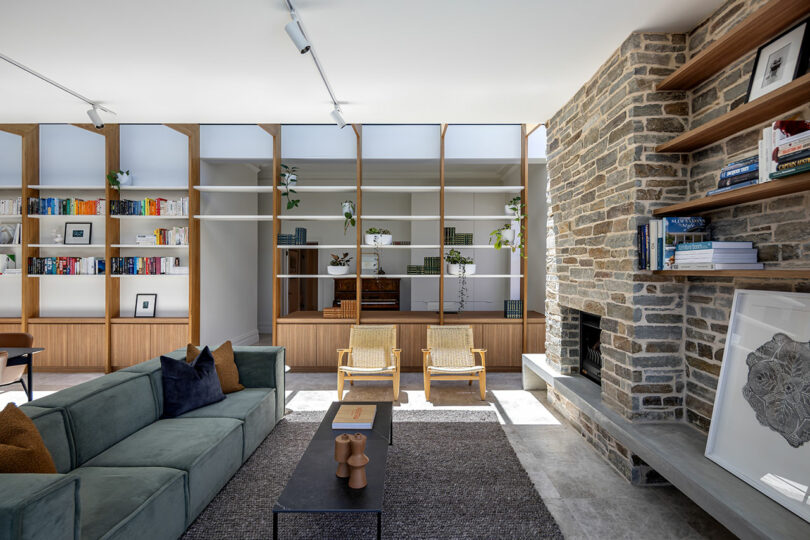 A living room with a stone fireplace and bookshelves.