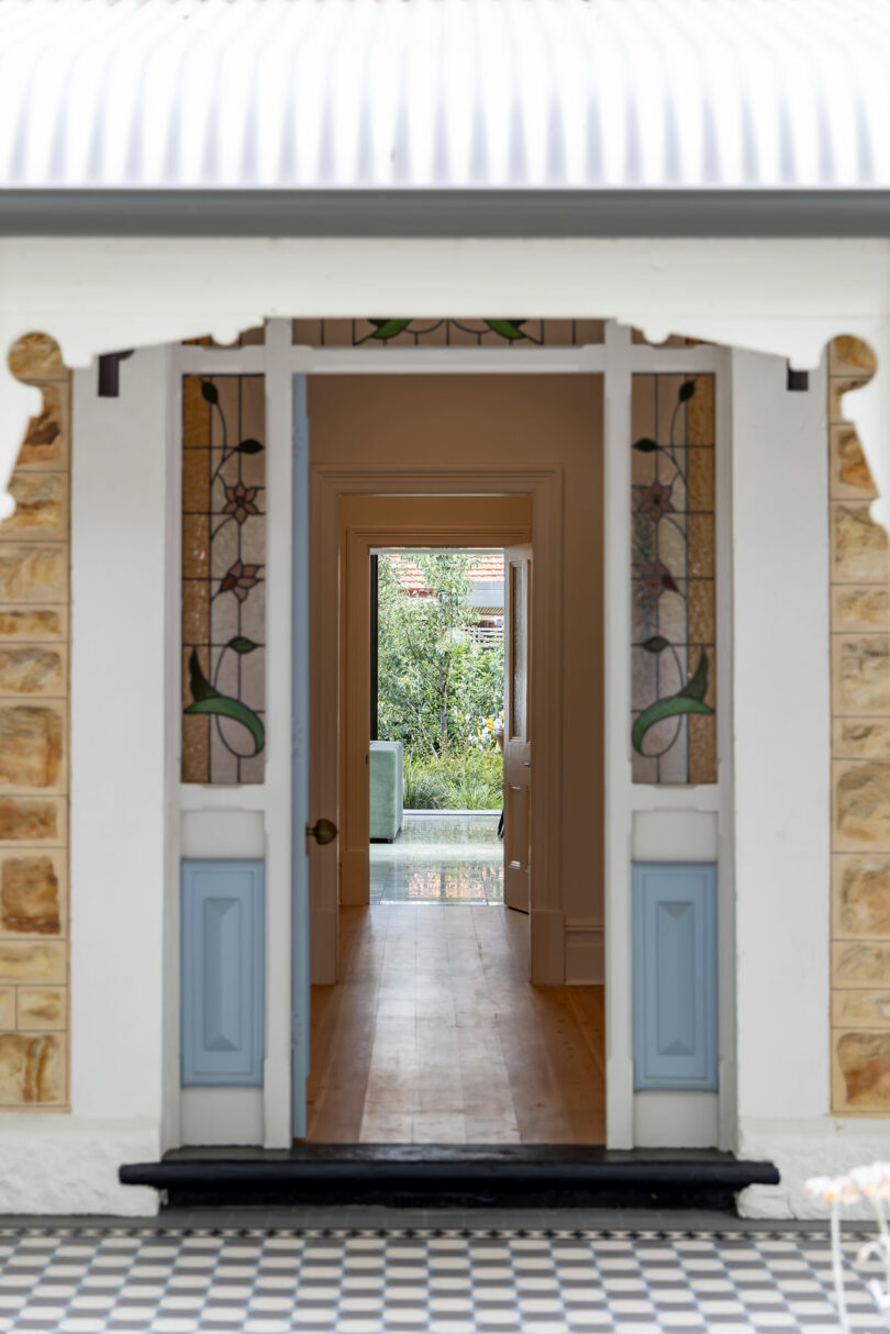 A doorway to a house with a blue and white tiled floor.