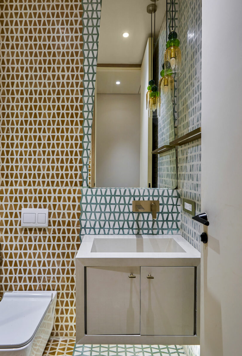 Modern bathroom featuring colorful patterned tiles, glass shower enclosure, and white fixtures.