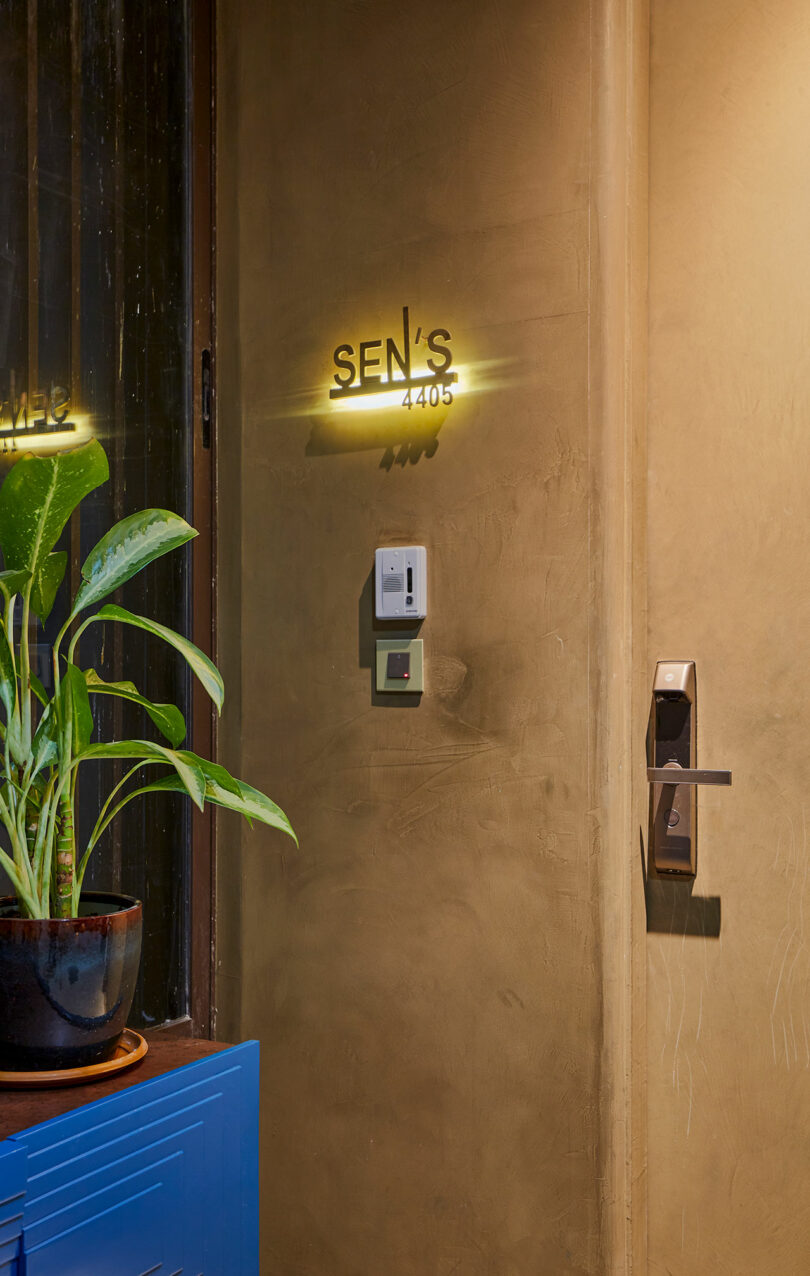 A warmly lit entrance with a nameplate above a doorbell and intercom.