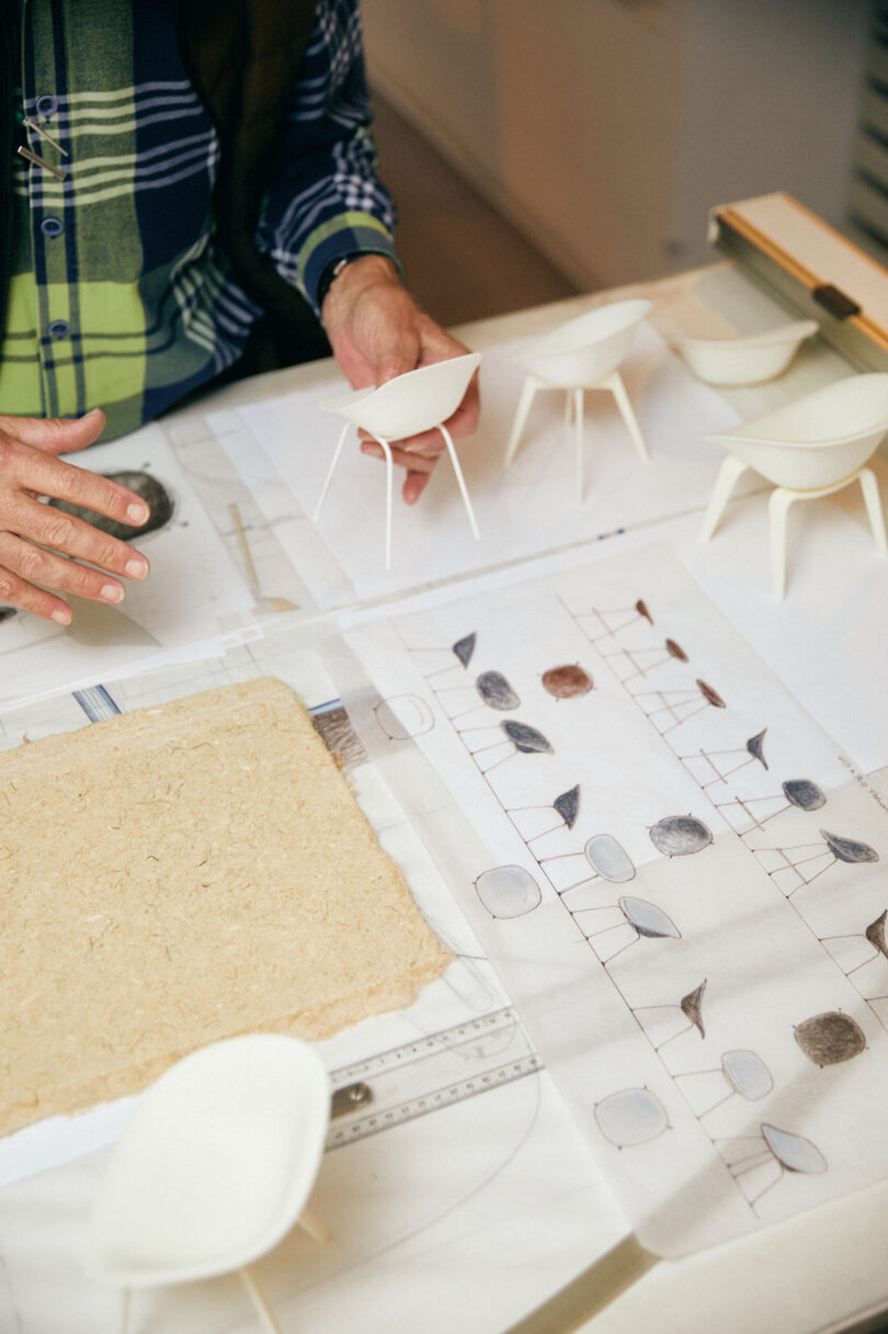 hand holding chair prototype on a table of sketches